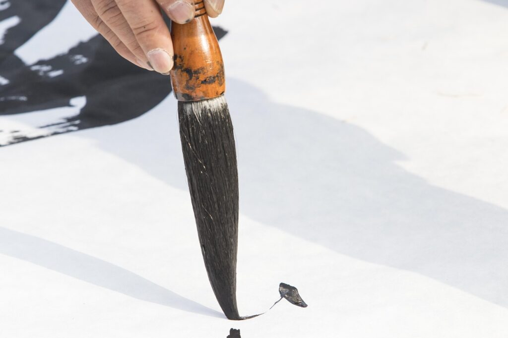 Une personne est en train de faire de la calligraphie chinoise au pinceau - Agrandir l'image, fenêtre modale