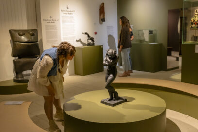 Une visiteuse, penchée vers l'avant, regarde plus en détail une oeuvre sculptée d'Auguste Rodin - Agrandir l'image, fenêtre modale