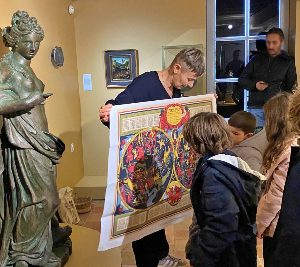 Une médiatrice présente une carte du ciel à des visiteurs vus de dos dans une salle du musée - Agrandir l'image, fenêtre modale
