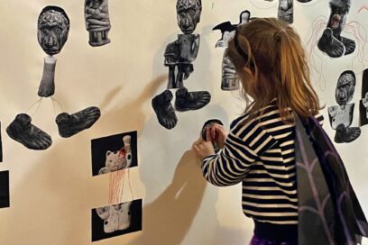 Vue d'une petite fille de dos qui colle des images sur un mur blanc - Agrandir l'image, fenêtre modale